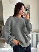 Person wearing a gray sweater taking a mirror selfie indoors.