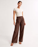 Woman wearing a white top and brown high-waisted pants on a white background
