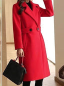 Person wearing a red coat holding a black handbag indoors.