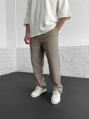 Person wearing beige ribbed pants and white sneakers against a plain background