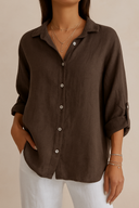 Person wearing a brown button-up shirt and white pants on a beige background