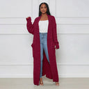 Woman wearing a long burgundy cardigan over a white top and blue jeans against a white background
