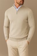Man wearing a beige sweater and pants against a brown background