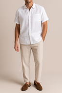 Man wearing a white short-sleeve shirt and beige pants against a beige background