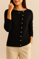 Woman wearing a black cardigan with silver buttons on a beige background