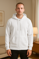 Man wearing a white hoodie in a room with a lamp and couch.