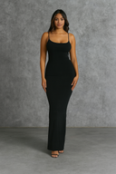 Woman wearing a black maxi dress against a gray background
