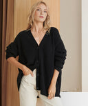 Woman wearing a black cardigan over a white top with a neutral background