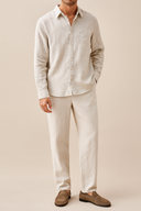 Man wearing a light beige linen shirt and pants on a plain background