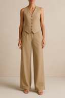 Person wearing a beige gilet and wide-leg pants on a beige background