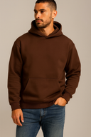 Man wearing a brown hoodie and blue jeans against a neutral background