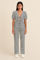 Woman wearing a black and white patterned jumpsuit on a beige background