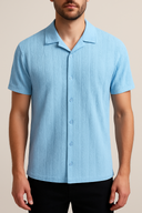 Man wearing a light blue textured short-sleeve shirt against a beige background