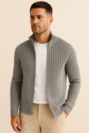 Man wearing a gray ribbed sweater over a white shirt with beige pants on a beige background