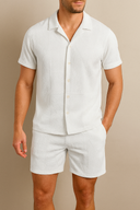 Man wearing A two-piece summer set consisting of a short-sleeved button-up shirt and matching shorts in white color.