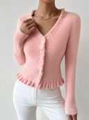 Pink knitted cardigan worn by a person on a plain background