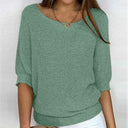 Green knitted sweater worn by a person on a white background