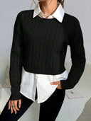 Person wearing a black cable knit sweater over a white shirt with a gray background