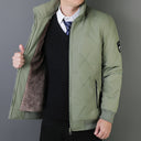 Person wearing a green quilted jacket with a gray background