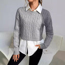 Person wearing a gray cable knit sweater over a white shirt with a neutral background