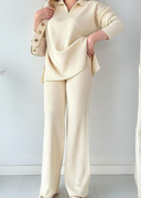 Person wearing a cream-colored outfit with a matching jacket against a white background