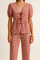 Person wearing a red and white patterned outfit on a beige background