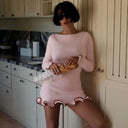 Woman in a pink dress holding a bagel in a kitchen