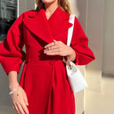 Person wearing a red coat holding a white handbag against a neutral background
