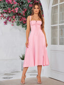 Woman wearing a pink dress standing in front of a white wall with flowers.