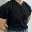 Person wearing a black short-sleeve shirt with a textured pattern on a plain background
