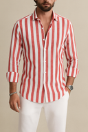 Man wearing a red and white striped shirt with rolled-up sleeves against a beige background