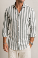 Man wearing a gray and white striped shirt with rolled-up sleeves against a neutral background