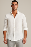 Man wearing a white button-up shirt and light gray pants against a plain background