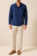 Person wearing a blue shirt and beige pants on a beige background