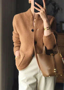 Person wearing a brown knitted cardigan and holding a matching brown handbag.