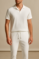 Man wearing a white textured shirt and pants against a beige background