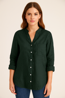 Woman wearing a dark green button-up shirt against a beige background