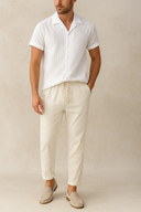 Man wearing a white striped shirt and beige pants against a beige background