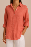 Person wearing a coral button-up shirt with rolled-up sleeves against a beige background