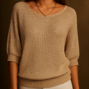 Beige knitted sweater worn by a person on a brown background