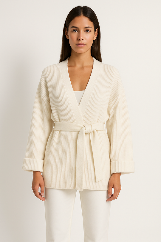 Woman wearing a cream ribbed knit cardigan with a belt on a white background