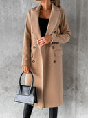 Person wearing a beige coat holding a black handbag against a gray background