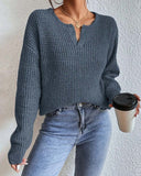 Person wearing a blue knitted sweater and jeans, holding a coffee cup against a plain background