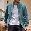 Man wearing a teal jacket over a white shirt, standing next to a car.