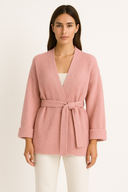 Woman wearing a pink ribbed knit cardigan on a beige background