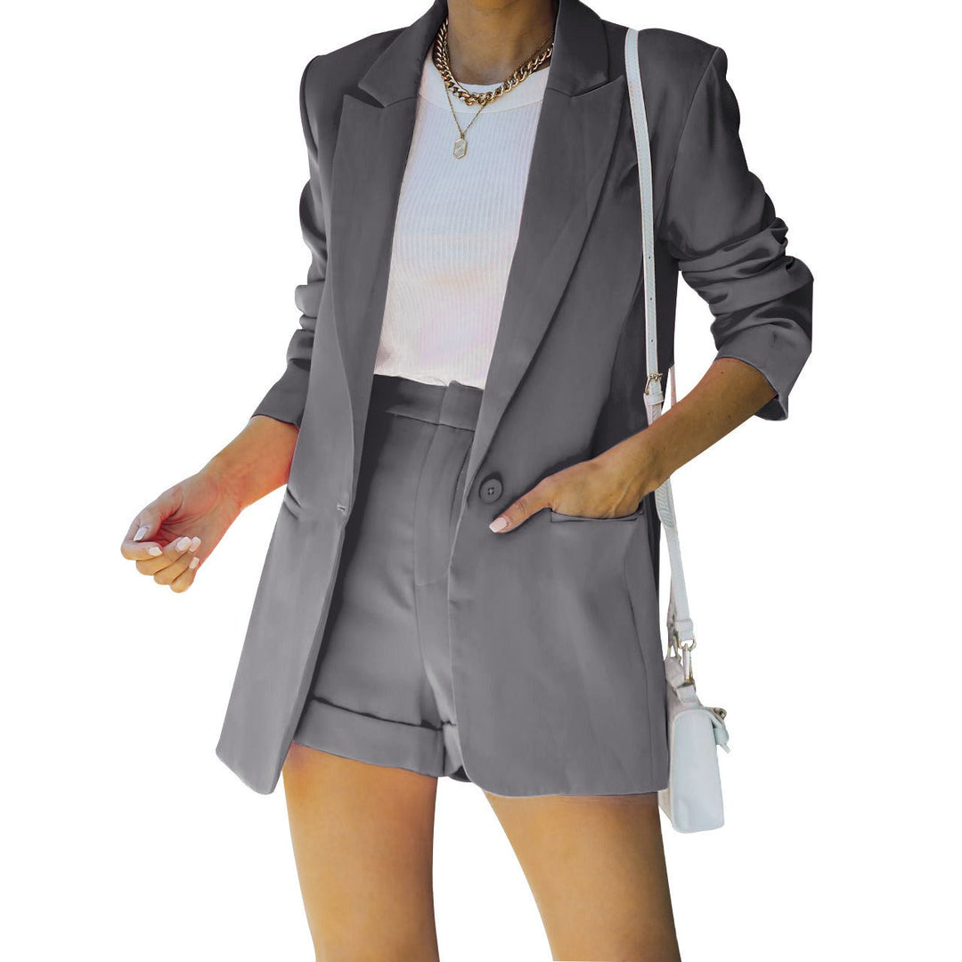 Person wearing a gray blazer and shorts set with a white top on a white background