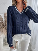 Person wearing a navy blue cable knit sweater with white trim, standing indoors.