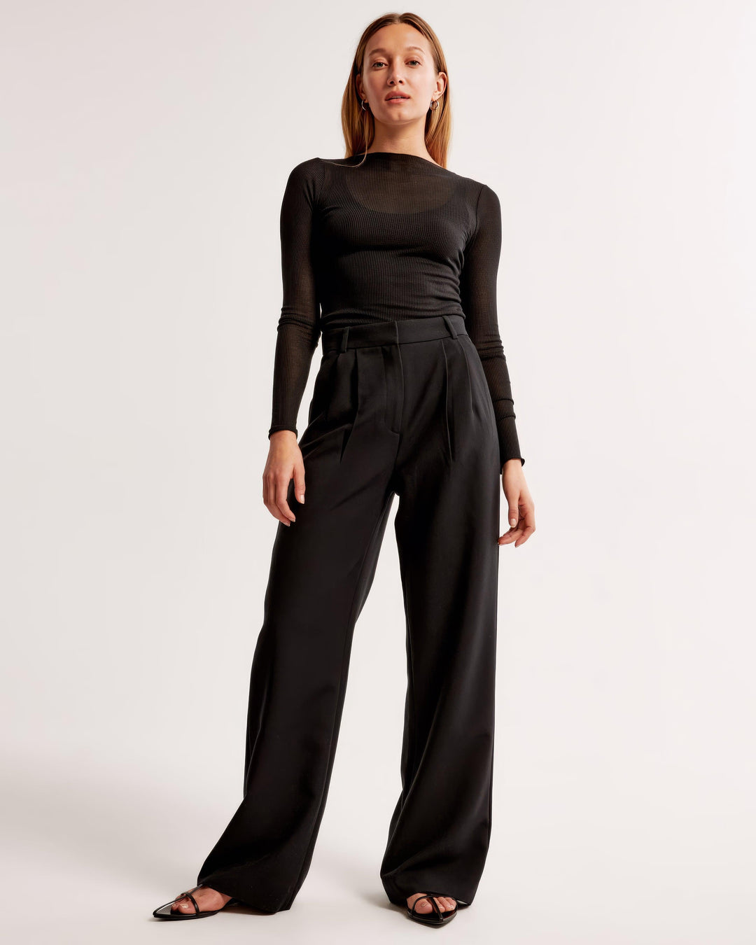 Woman wearing a black outfit with wide-leg pants on a white background
