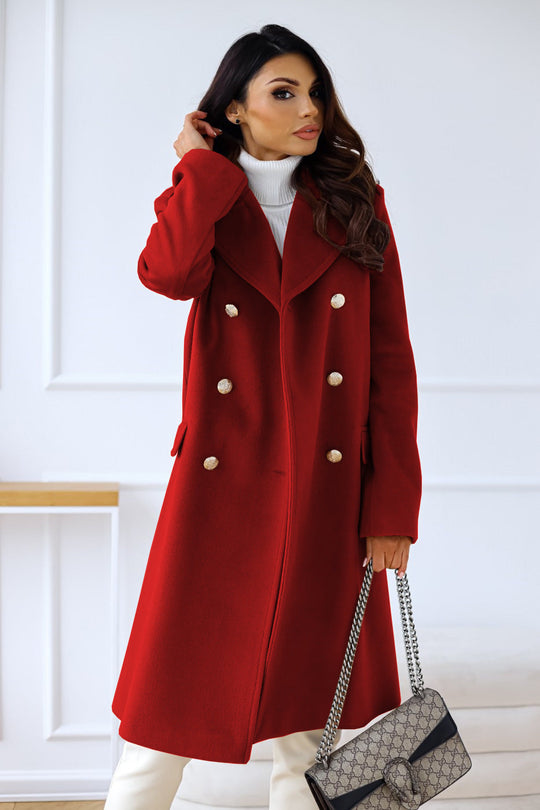 Woman wearing a red coat with white buttons, holding a black handbag against a white background