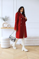 Woman wearing a red coat and white boots in a minimalistic room.